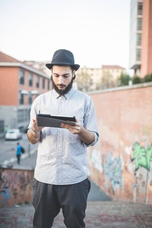 young handsome hipster gay modern man using tablet in townの写真素材