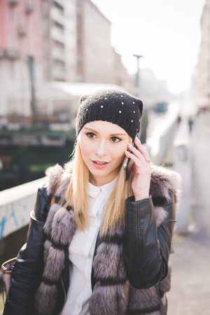 young beautiful blonde straight hair woman in the city calling with smartphoneの写真素材