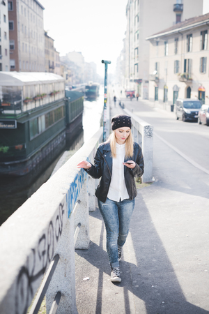 young beautiful blonde straight hair woman in the city using smartphone connected online on internetの写真素材