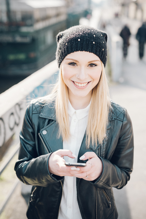 young beautiful blonde straight hair woman in the city using smartphone connected online on internetの写真素材