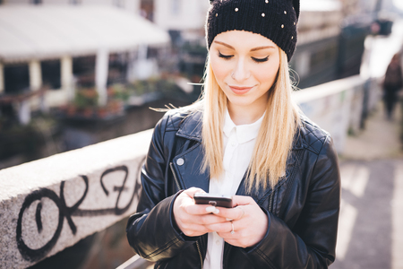 young beautiful blonde straight hair woman in the city using smartphone connected online on internetの写真素材