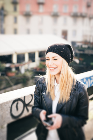young beautiful blonde straight hair woman in the city using smartphone connected online on internetの写真素材