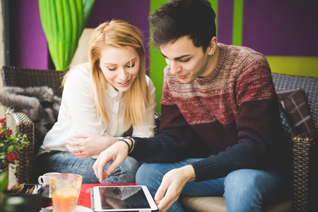 young beautiful couple lovers sitting at the bar using wireless tablet connected onlineの写真素材