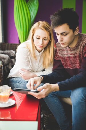 young beautiful couple lovers sitting at the bar using wireless tablet connected onlineの写真素材