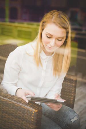 young beautiful blonde straight hair woman in the city sitting at the restaurant using tabletの写真素材