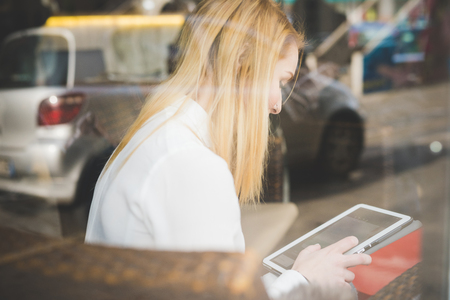 young beautiful blonde straight hair woman in the city sitting at the restaurant using tabletの写真素材