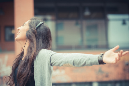 young beautiful brunette woman listening music with headphones in the cityの写真素材
