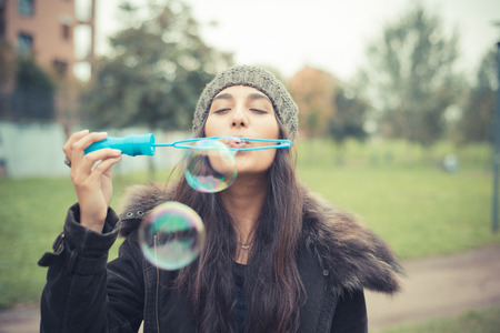 young beautiful brunette woman blowing bubbles soap in the city