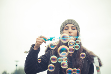 young beautiful brunette woman blowing bubbles soap in the cityの写真素材