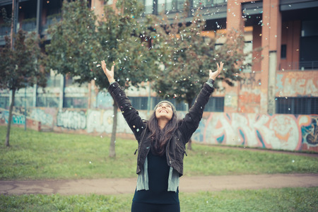 young beautiful brunette woman playing with confetti carnival in the cityの写真素材