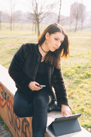 young beautiful woman using tablet and smartphone in the cityの写真素材