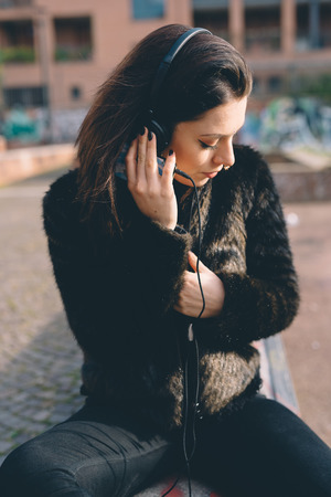 young beautiful woman listening to music with headphones in the cityの写真素材