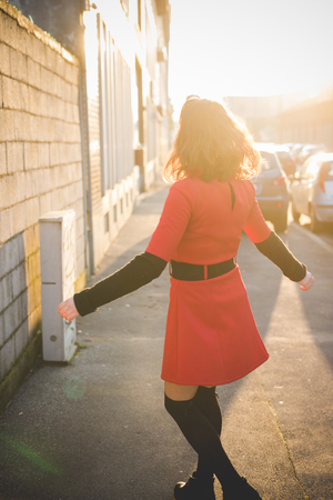 young beautiful red dressed vintage hipster woman in street townの写真素材