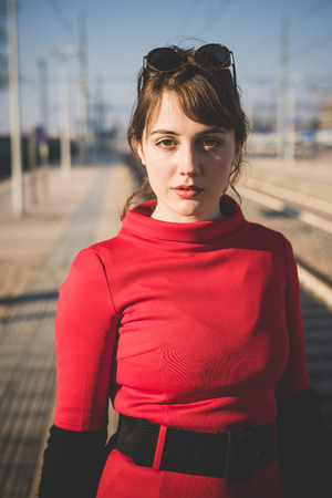 young beautiful red dressed vintage hipster woman in street townの写真素材