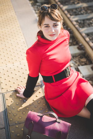 young beautiful red dressed vintage hipster woman in street townの写真素材