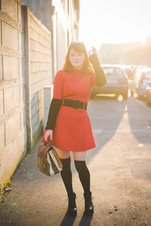 young beautiful red dressed vintage hipster woman in street townの写真素材