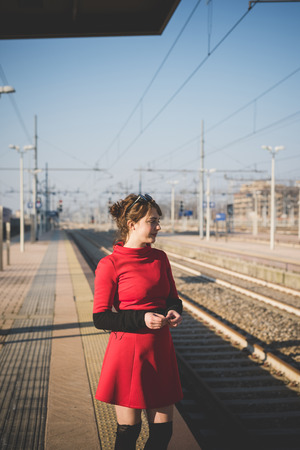 young beautiful red dressed vintage hipster woman in street townの写真素材