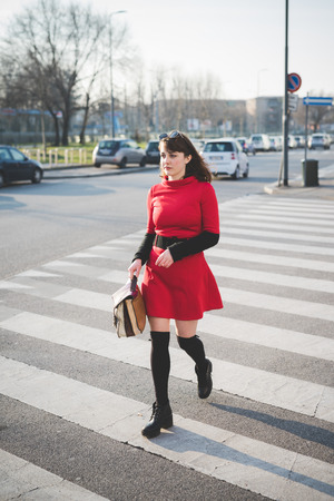 young beautiful red dressed vintage hipster woman in street townの写真素材