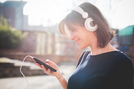 young pretty woman in town listening music with headphonesの写真素材