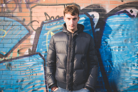 Young and handsome man in the city, wearing blue jeans and a blue jacket.