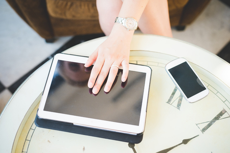 Close up on the hand of a young handsome caucasian girl using technological devices like tablet and smartphone - multitasking, technology conceptの写真素材