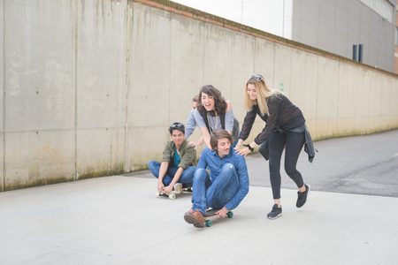 Group of young multiethnic friends having fun laughing, and smiling, racing sitting on their...