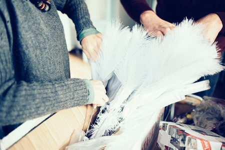 Close up on the hands of couple of young handsome caucasian man and woman unpacking christmas tree, looking downward, smiling - christmas, holiday, winter conceptの写真素材
