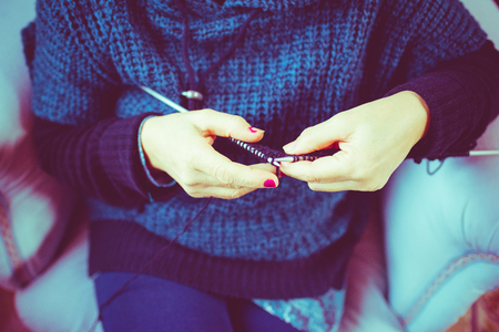 Close up on the hands of a woman knitting with knitting needles and woolen yarn, filtered vintage - handcraft, hobby conceptの写真素材
