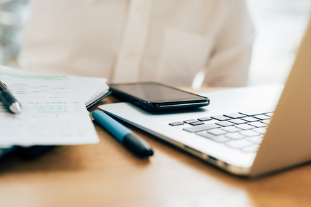 Close up on a smartphone leaning on a laptop with pencil and organizer leaning near them - working, multitasking, technology conceptの写真素材
