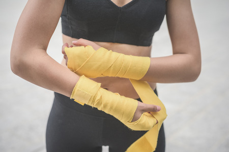Close up of a young handsome caucasian brown hair woman wrapping her hands with a band, preparing herself for boxing training - sportive, healthy, fitness conceptの写真素材