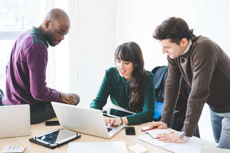 Multiracial contemporary business people working connected with technological devices like tablet and laptop, talking together - finance, business, technology conceptの写真素材