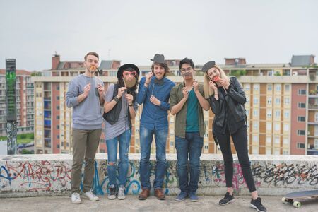 Group of young multiethnic friends posing playing with carton template in shape of hat, mustache, pipe, glasses, bow tie - carefree, friendship, happiness conceptの写真素材