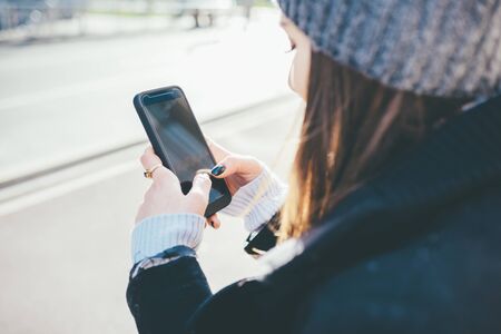 Close up on the hands of a young woman holding a smart phone tapping the screen - technology, social network, communication conceptの写真素材