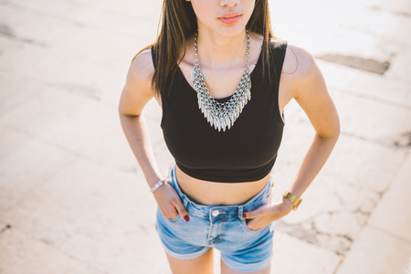 Top view of young handsome asiatic long brown straight hair woman posing in the city, hands in pocket - serene, happiness, carefree conceptの写真素材