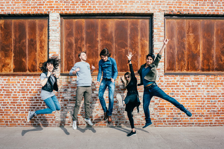 Group of young beautiful multiethnic man and woman friends having fun jumping outdoor in the city - happiness, friendship, teamwork concept