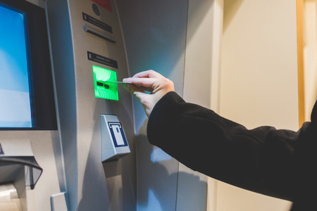 Close up on the hand of man inserting debit card in ATM machine - money, cash concept