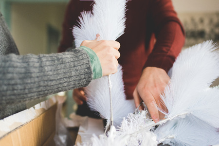 Close up on hands of couple of young handsome caucasian man and woman unpacking christmas tree, looking downward, concentrate - christmas, holiday, winter conceptの写真素材