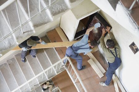Workers move the safe on a staircaseの写真素材