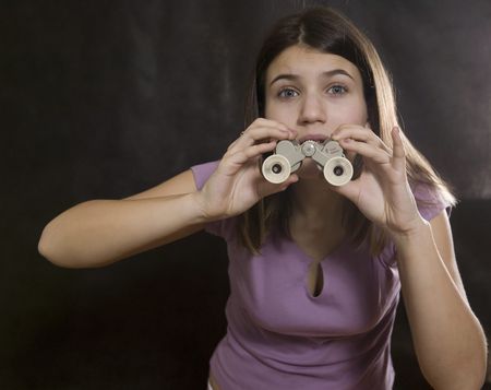 Girl with binoculars on black.の写真素材