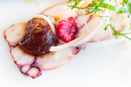 Cold appetizer of boiled octopus, cut into thin slices with a confit of cherry tomatoes, berries, grated cheese, julienne of fresh vegetables.の写真素材