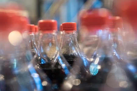 Transparent plastic bottles with a carbonated drink on the conveyorの写真素材