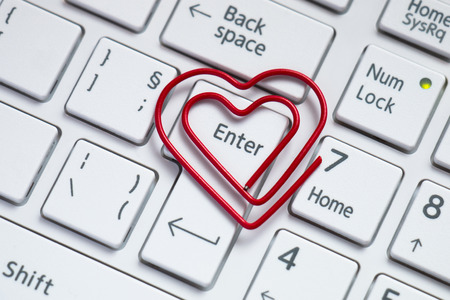 Love shaped paper clip on white keyboard.の写真素材