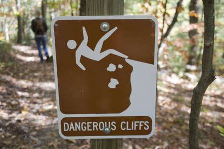Lady standing beyond dangerous cliff signの写真素材