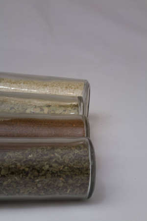 Four spice jars in line with chili powder, parsley, garlic, and bay leavesの写真素材