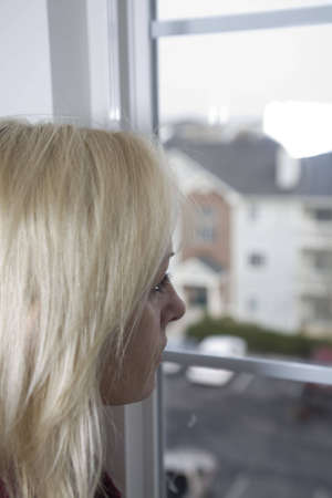 Woman staring out the window deep in thoughtの写真素材