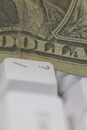 Close-up of a dollar bill next to the question mark key of a computer keyboard. Representation of question of dollar value in business.の写真素材