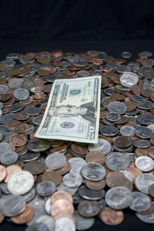 US currency coins and a twenty dollar bill on top. Turning coins into bills through savings.の写真素材
