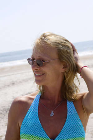 Adult woman at beach with hand running through her hair while looking to the sideの写真素材