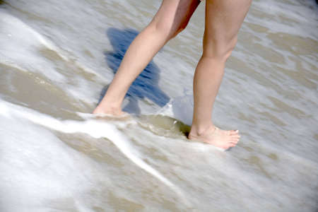 Legs of a sexy woman walking into the surf at the oceanの写真素材