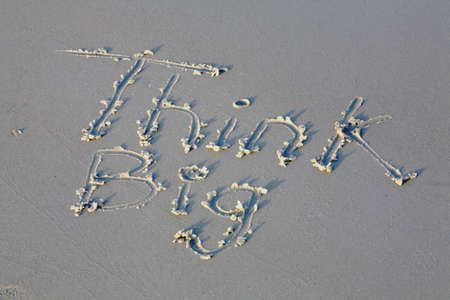 Message to think big drawn in the sandの写真素材